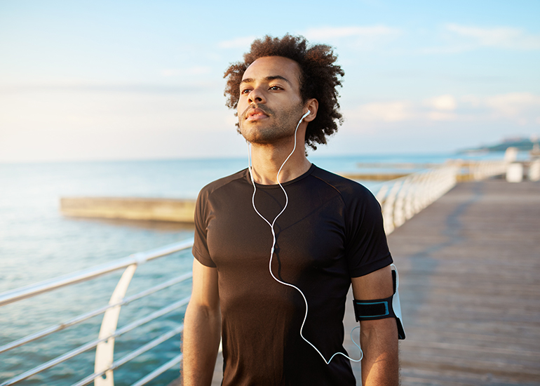 Man with earphones jogging by ocean